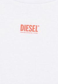 Camiseta blanca de algodón con un destacado logo rojo de "DIESEL" y el texto "PARA UNA VIDA EXITOSA" en una fuente más pequeña debajo.
