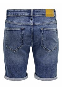 Pantalones cortos de mezclilla de color azul desvanecido, con dobladillo enrollado y dos bolsillos traseros de parche. Presenta una etiqueta de cuero marrón en la cintura.
