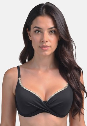 Soutien-gorge nero con un design frontale intrecciato, bordatura dorata lungo il décolleté, spalline regolabili e una texture di tessuto liscia.