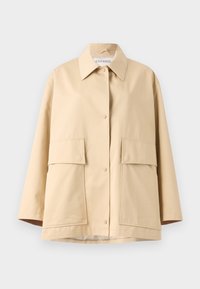 Bež bleiser, mis on valmistatud sileda kangaga, klassikalise kraega, kahe suure esisekotti ja lõdva lõikega. Sulgub nähtavate nuppudega.