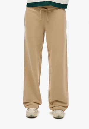 Pantalones de chándal beige con un corte holgado, cinturilla elástica y cordón ajustable. Textura suave, diseño de pierna recta y sin patrones visibles.