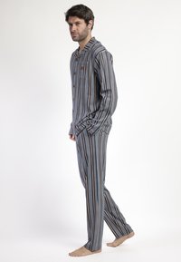 Conjunto de pijama a rayas que incluye una camisa con botones y pantalones a juego. Fabricado con tela suave, en tonos de azul, marrón y crema.
