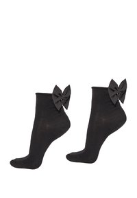 Schwarze Knöchelsocken aus weichem Stoff mit einer strukturierten Oberfläche, die große schwarze Schleifen auf der Rückseite haben.