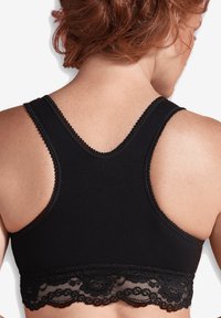 Svart sport-bh med spetsbesättning längst ner. Har en racerback-design och mjukt tyg, med fina scallop-detaljer längs kanterna.