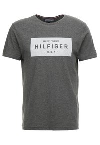 Grå bomulds T-shirt med korte ærmer, der har et hvidt rektangulært grafik, som skriver "NEW YORK HILFIGER U.S.A." med sort tekst.