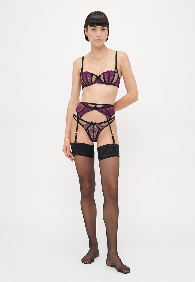 Ensemble de lingerie en dentelle mettant en avant des couleurs violet et noir, des panneaux transparents, des motifs complexes et des bretelles ajustables ; comprend un porte-jarretelles et des bas jusqu'à la cuisse.