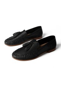 Sorte læderloafers med kvaster foran, synlig syning omkring tåen og brune lave hæle, vist side om side på hvid baggrund.