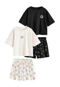 Sæt af tre bomuldsbeklædningsgenstande: sort T-shirt med smiley blomsterdesign, cremefarvet T-shirt med hjertegrafik og sorte shorts med hvidt mønster af hjerter og stjerner.