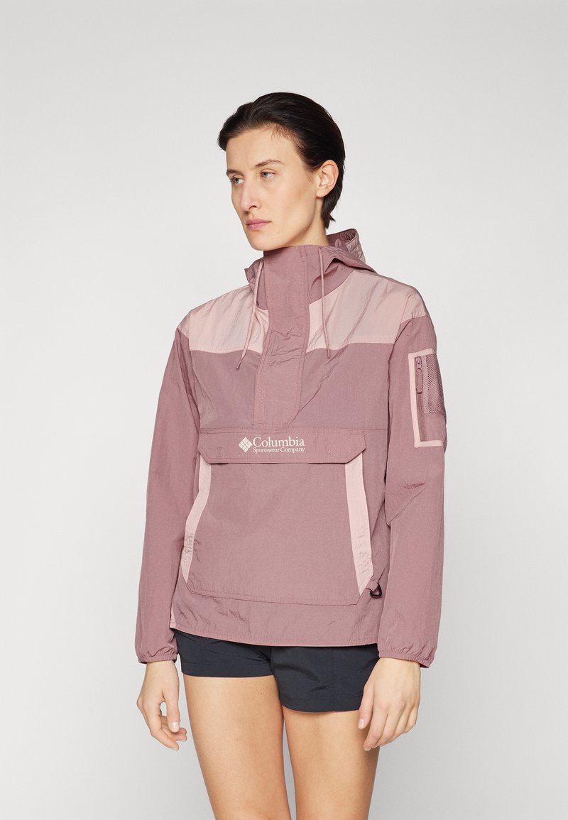 Giacca anorak leggera bicolore rosa con polsini elasticizzati, tasca frontale, cappuccio regolabile e logo ricamato. Texture liscia.