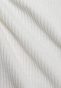 Weißer gerippter Stoff mit strukturierter Oberfläche, der diagonale Muster und eine weiche Strickkonstruktion aufweist.
