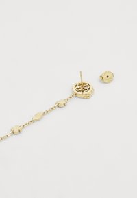 Orecchini in oro con un design floreale e accenti a forma di foglia. Presentano una chiusura a posteriore e un dettaglio del logo sul retro.
