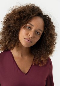 V-hals, losvallend top in diep bordeauxkleurig jersey materiaal met korte mouwen en een gladde textuur, met een subtiele glans.