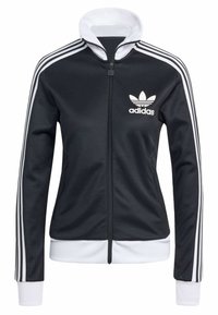 Svart idrottsjacka med vita detaljer, har dragkedja, hög krage och tre vita ränder på ärmarna, med Adidas-logotyp på bröstet.
