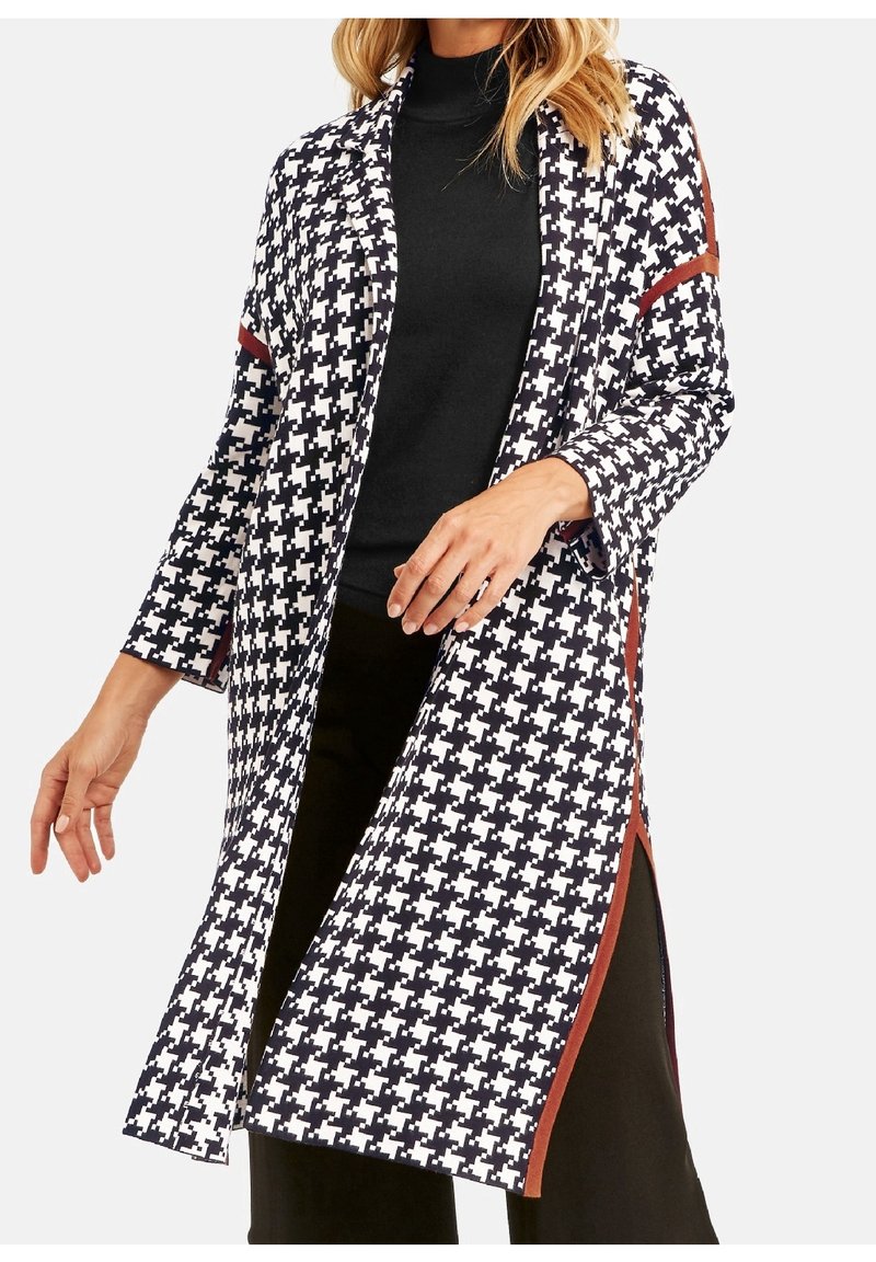 Cardigan long et ouvert en motif pied-de-poule noir et blanc, avec des accents rouges sur les bords, doté de manches trois-quarts et de fentes latérales.
