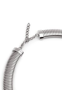 Collier en métal avec un design enroulé, présentant une finition argentée brillante et un fermoir avec une chaîne. Contient un détail de marque gravé.