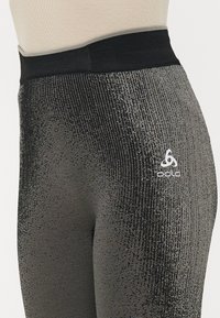 Svart og gråmønstrede leggbukser med høy midje, med et teksturert design og Odlo-logoen nær hoftområdet.