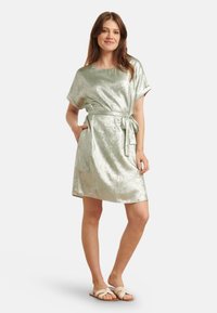 Short-sleeved, metallic light green dress with a wrap-style belt, featuring a loose fit and knee-length hem. Smooth texture and subtle shine.