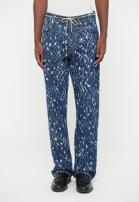 Mėlynos džinsinės kelnės su raštuotu tekstūru, turinčios baltus akcentus. Tiesios kojos dizainas, elastingas juosmuo su raišteliu ir priekinės kišenės.