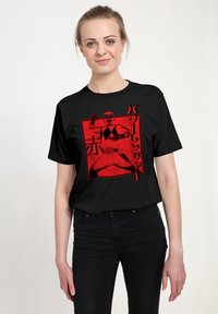 Černé tričko s odvážným �červeným grafickým designem postavy v akční pozici, se japonským textem a akcenty. Krátké rukávy, kulatý výstřih.