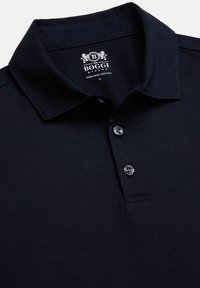 Marineblauwe polo gemaakt van 100% Pima-katoen met een kraag, drie knoopjes en een zachte, gladde textuur.