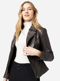 Braune Leder-Motorradjacke mit tailliertem Design, strukturierten Schulterakzenten, Reißverschluss und leichtem Erscheinungsbild. Das Modell trägt ein weißes Oberteil.