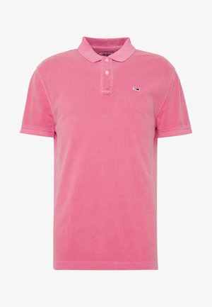Polo en coton rose, doté d'un col, d'une patte de boutonnage à deux boutons et d'un petit logo sur la poitrine. Manches courtes et tissu texturé.