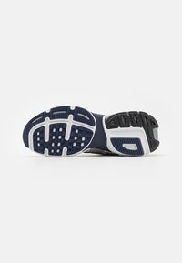 Shoe outsole with a dark blue and black rubber design featuring textured grip patterns and white midsole accents.