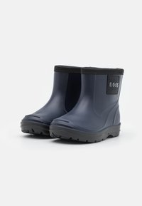 Bottes de pluie courtes en caoutchouc bleu marine avec semelles et finitions noires, arborant un petit écusson noir sur le côté.