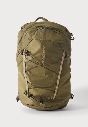 Mochila Salomon verde oliva con compartimentos con cremallera, correas ajustables, cordón elástico frontal y asa superior sobre fondo blanco liso.
