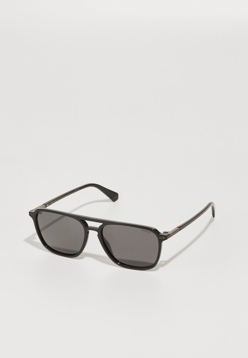 Óculos de sol polarizados pretos com lentes retangulares, detalhes em metal e hastes finas, apresentando uma textura subtil na armação.