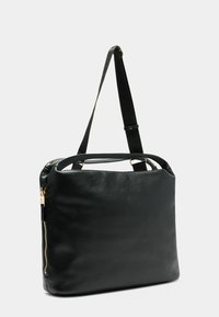 Schwarze Lederhandtasche mit einem verstellbaren Tragegurt und einem goldenen Reißverschlussdetail, vor einem plain weißen Hintergrund.