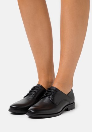 Chaussures en cuir noir à lacets avec une finition lisse, bout arrondi, petit talon et détails surpiqués sur les côtés.