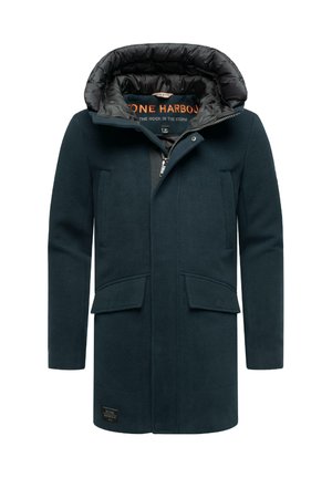 Dark green long coat made of textured fabric, featuring a puffer hood, two front pockets, and a visible logo label near the hem.