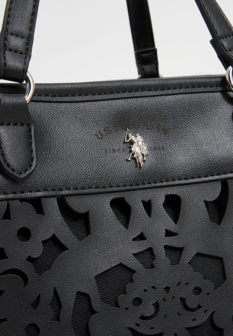 Schwarze Lederhandtasche mit filigranen ausgestanzten Blumenmustern, silbernem Zubehör und einem auffälligen Logodetail über den Ausstanzungen.