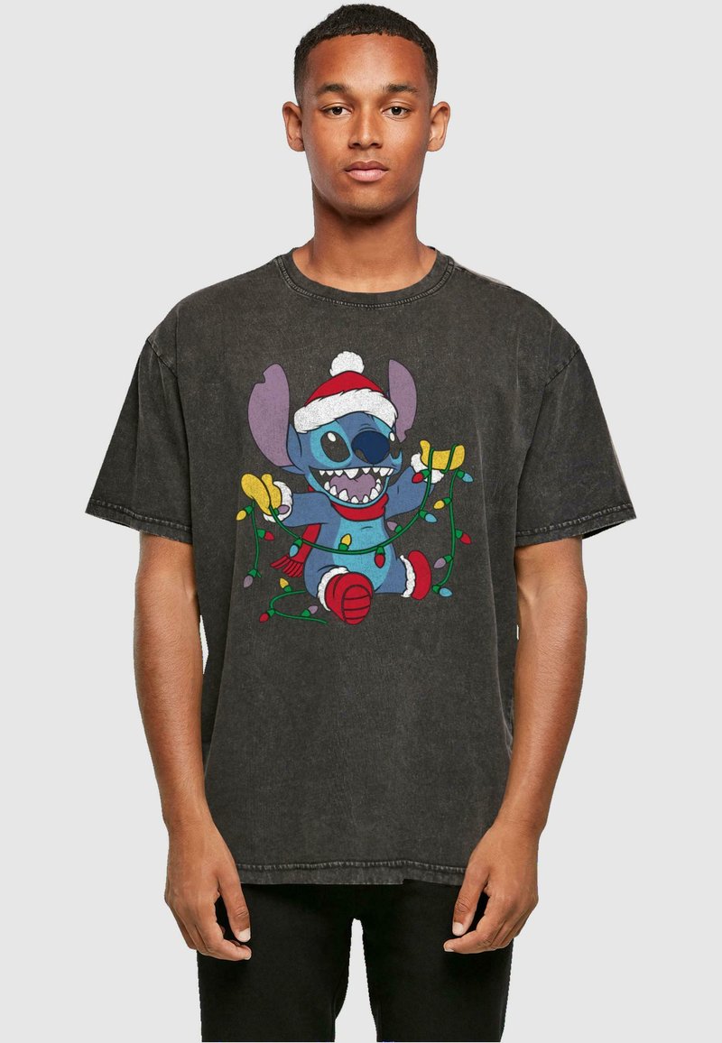 Camiseta negra de gran tamaño, con un personaje de dibujos animados colorido que lleva un gorro de Santa, rodeado de luces navideñas. Textura de tela suave y desgastada.