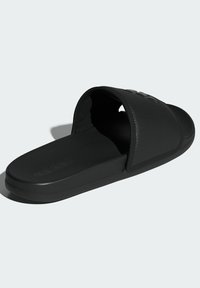 Black slide sandal with a textured upper, cushioned footbed, and flat sole. Features embossed logo on the strap and a smooth finish.