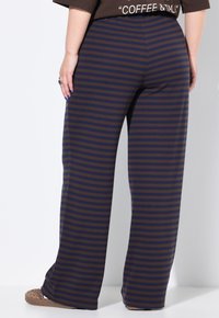 Pantaloni a gamba larga a righe in blu scuro e marrone. Tessuto morbido con una vestibilità rilassata. Presentano strisce orizzontali e una cintura comoda.