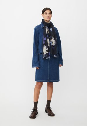 Vestito di jeans con maniche lunghe e scollo con colletto. Sciarpa nera con motivo floreale. Scarpe marroni con lacci.