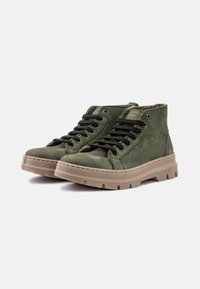 Stivaletti alla caviglia in suede verde con lacci neri, occhielli in metallo e una suola in gomma beige testurizzata. Presentano un colletto imbottito per il comfort.