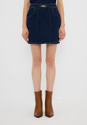 Mini-jupe en jean avec une taille ajustée, détail de ceinture à boucle dorée et couleur bleu foncé. Comprend des poches avant doubles et des coutures contrastées.