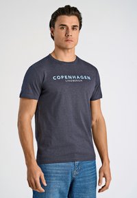 Mörkgrå kortärmad t-shirt med "COPENHAGEN" och "LINDBERGH" tryckt i ljusblått. Materialet verkar mjukt, åtsittande design med rund hals.