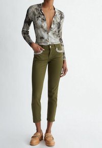 Top de manga larga con tejido acanalado y patrón de teñido anudado en gris y marrón, combinado con vaqueros verde oliva con bolsillos adornados y mocasines de plataforma color canela.