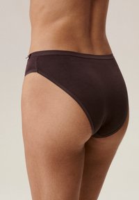 Brązowa bielizna bawełniana o wysokim kroju, gładkiej fakturze i minimalnym ściegu. Posiada mały dekoracyjny akcent z metalu.