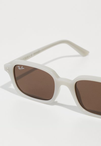 Слънчеви очила Ray-Ban с бяла пластмасова рамка и кафяви лещи с нюанс. Знакова квадратна форма и деликатно лого на рамката.