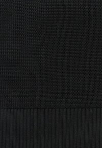 Tessuto lavorato a maglia nero con un motivo testurizzato, dotato di un orlo a coste nella parte inferiore, che conferisce una qualità morbida e leggermente elasticizzata.