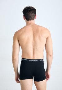 Schwarze Boxer-Briefs aus weichem Stoff mit einem gerippten Bund, der das Logo "BJÖRN BORG" trägt. Die Passform ist körpernah.