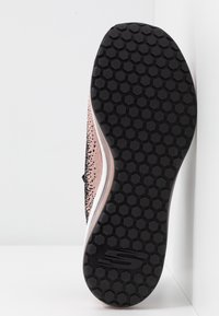 Svart och rosa sportskosula med ett bikakesmönster, vadderad vit mellansula med en slät yta och logodetalj.