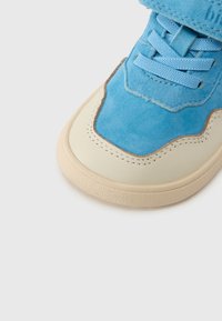 Ανδρικό αθλητικό παπούτσι από γαλάζιο σουέτ με κρέμα σόλα από καουτσούκ, με υφή στο σχεδιασμό, μπλε κορδόνια και επένδυση στον αστράγαλο για υποστήριξη.