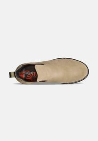 Zapato slip-on de ante beige con inserciones elásticas en los laterales, costuras beige y una plantilla acolchada roja con patrón. Presenta una pestaña en bucle en el talón.