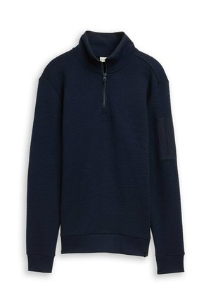 Felpa pullover blu navy con un motivo a nido d'ape, collo alto, zip a un quarto e polsini e orlo a costine. Dettaglio della tasca sul maniche sinistro.